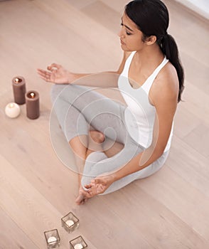 Woman, calm meditation and spiritual in a home with candles and chakra for balance and mindfulness. Morning, wellness