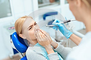 The woman came to the dental clinic. She sits in the dental chair and afraid