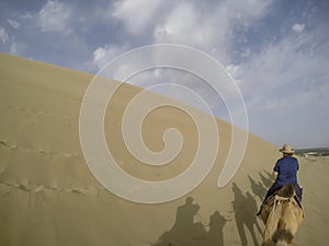 Woman on camel in Taklamakan Desert, China