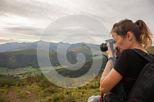 Woman with camera Canon taking picture in mountains. Photographer with camera and backpack. Tourist girl on picturecque landscape