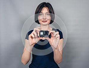 Woman with  camera. Everyday clothes. Gray background.  Gopro. Action camera