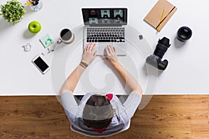 Woman with camera working on laptop at table