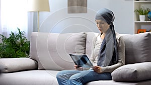 Woman with cancer sitting on sofa and looking at lung x-ray, hoping for healing