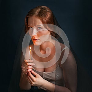 Woman with candle under veil. Halloween photo