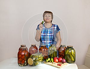 woman with canned pickles cucumbers and tomatoes, pickled vegetables, homemade food, woman eats cucumber, white adult woman laughs