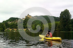 Woman canoeing by the river in front of Castellnaud le Chapelle