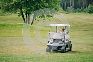 woman in cap riding golf cart at golf course