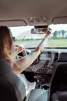 Woman in car, adjusts and rearview mirror, driving safety in car, parking and rear traffic. Reverse parking in car