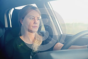 Woman in a car while driving. Profile photo of a beautiful blonde woman with long hair