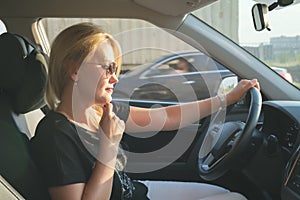 Woman in a car while driving. Profile photo of a beautiful blonde woman with long hair wearing sunglasses