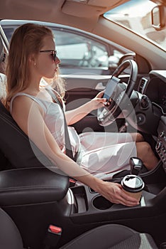 Woman car interior holds cup coffee tea, reads writes message mobile phone parking lot near shopping center. A long wait