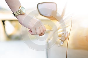 Woman with car key. Opening car door. WomanÂ´s hand unlocking a door on a car. Sunlight. Transportation.