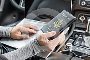 Woman in the car with laptop and american passport. Travel concept.