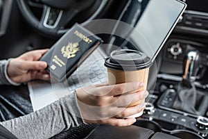 Woman in the car with laptop and american passport. Travel concept.