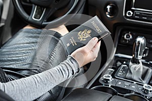 Woman in the car with laptop and american passport. Travel concept.