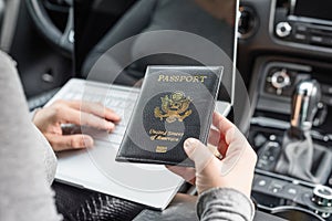 Woman in the car with laptop and american passport. Travel concept.