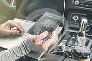 Woman in the car with laptop and american passport. Travel concept.