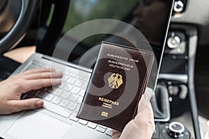 Woman in the car with laptop and germany passport. Travel concept.