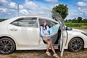 Woman in a car looking at a map to reach the holiday destination with blue sky