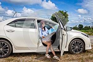 Woman in a car looking at a map to reach the holiday destination with blue sky