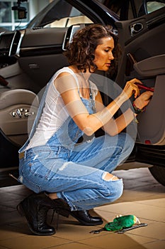 Woman car mechanic in blue overalls adjusts the car door
