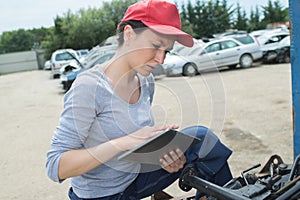 Woman car mechanician repairs engine car outdoors