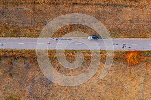 Woman and car on road through grassy wastelands, aerial view