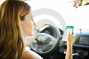 Woman in car using GPS navigator on her phone