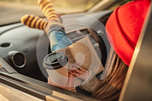 Woman in a car in warm woolen socks yellow is reading a book at sunset. Cozy autumn weekend trip. Freedom of travel