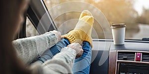 Woman in a car in warm woolen yellow socks on the car dashboard. Cozy autumn weekend trip. Concept of freedom of travel