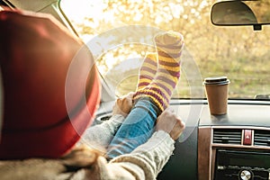 Woman in a car in warm woolen yellow socks on the car dashboard. Cozy autumn weekend trip. Concept of freedom of travel