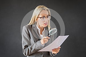 Woman carefully reading business contract with magnifying glass