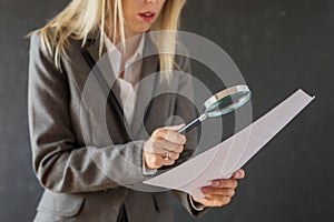 Woman carefully reading business contract with magnifying glass