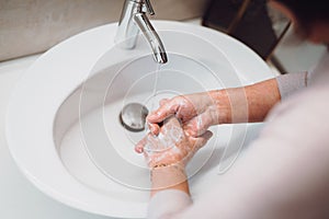 woman carefully washing hands with soap and sanitiser in bathroom. top view, details of hygiene, disinfecting hands