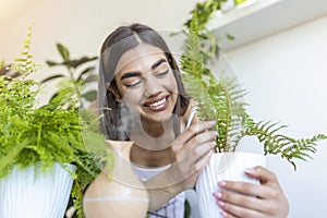 Woman caring for plants next to steam aroma oil diffuser on the table at home, steam from humidifier. Humidification of air in