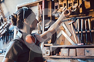 Woman carpenter choosing a tool to work on wood