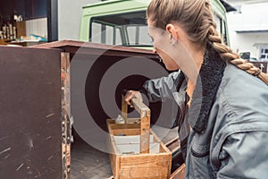 Woman carpenter loading tools in mobile workshop transporter