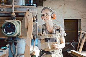 Woman carpenter in traditional carpentry adjusting the machine planer