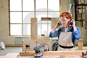 woman carpenter wearing headset before woodworking, cutting wood using power saw