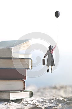 Woman carried by a balloon flies above a mountain of giant books