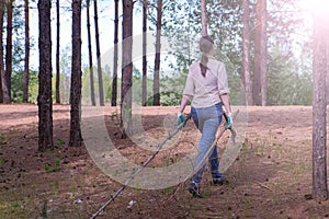 Woman carries felled trees to a forest scout`s camp for firewood, back view.