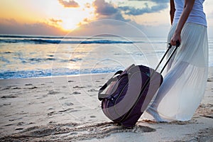 Woman carries your luggage at sandy beach