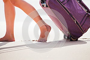 Woman carries your luggage at sandy beach