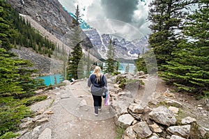 Woman carrying camera gear walks the Rockpile Trail at Moraine Lake in Banff National Park