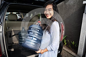 Woman carrying a gallon of water put in car trunk