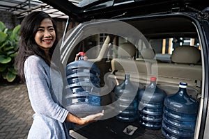 Woman carrying a gallon of water put in car trunk