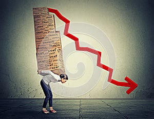 Woman carrying heavy boxes full of financial debt walking along gray wall background