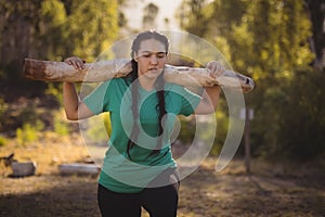 Woman carrying heavy wooden log during obstacle course