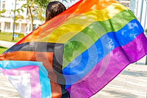 Woman carrying the LGBTQ progress pride rainbow flag