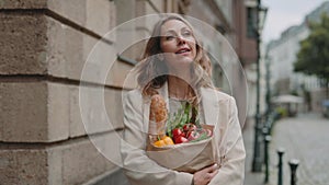 Woman carrying paper shopping bag with food outdoors